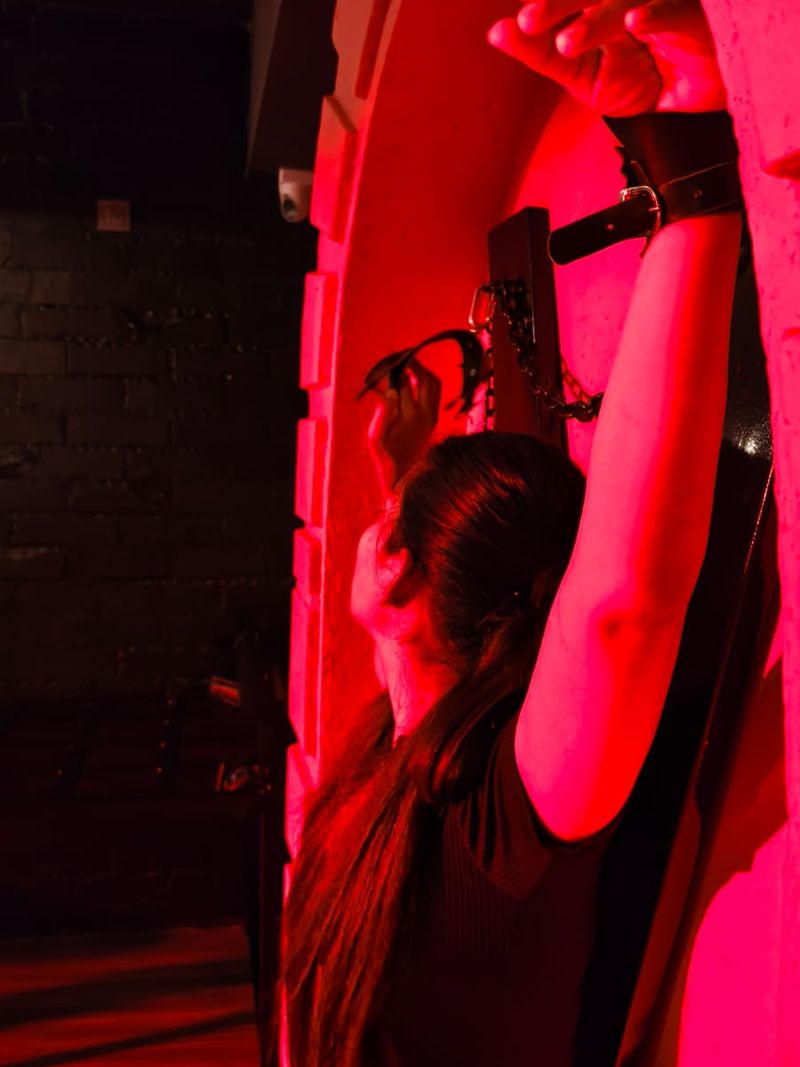 A guest cuffed with arms raised under red light