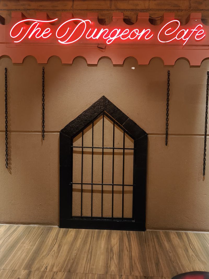 The Dungeon Cafe neon sign over the gated arch