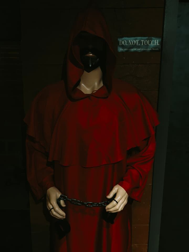A hooded figure in red holding chains